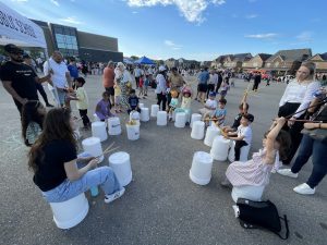 Children and instructor playing bucket drums as a group activity during a Bandology community music event