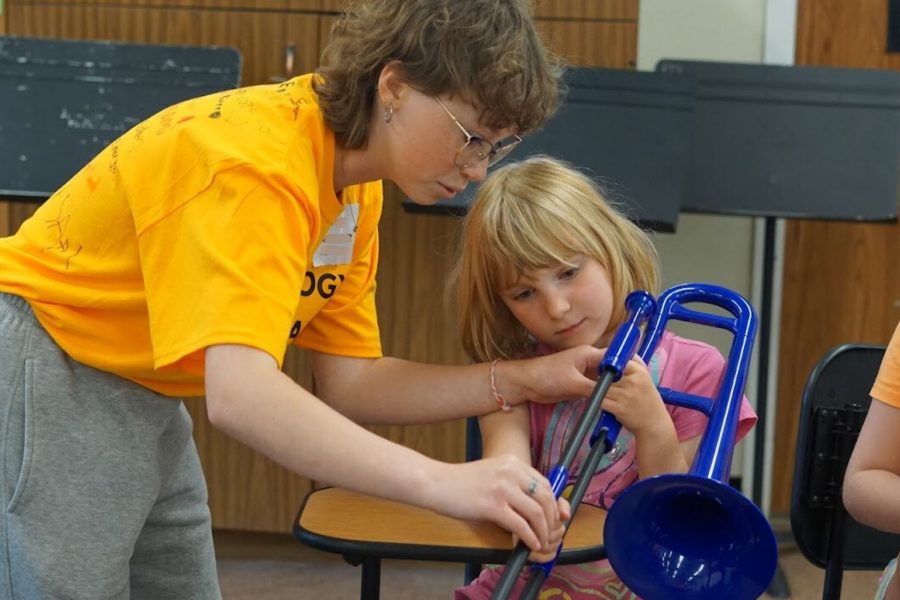 Music mentor instructing a camper playing trombone at Band Camp