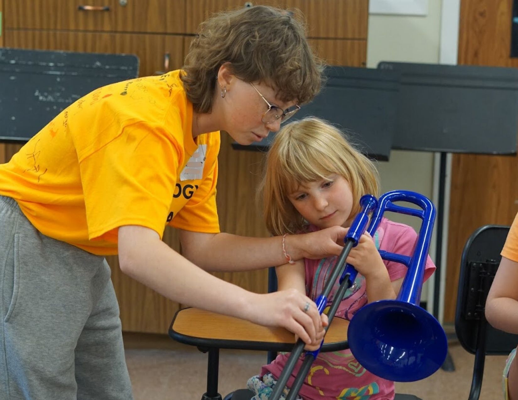 Music mentor instructing a camper playing trombone at Band Camp