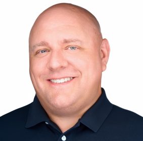 Brent Stevens smiling with a white background and black button up